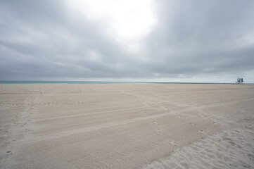Fototapeta na wymiar February, 15, 2023, Miami Beach, Florida, USA: deserted sand beach under clouds during winter