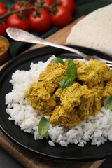 Delicious rice and chicken with curry sauce on wooden board, closeup
