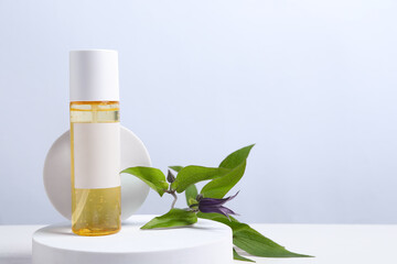 Bottle of cosmetic product and leaves on white wooden table. Space for text