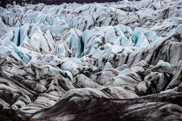 Glacier erosions in Iceland with black volcanic dust on the ice on a cold day in spring