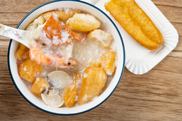 top view seafood porridge with crabs and shrimps and white shells and deep-fried dough sticks horizontal composition