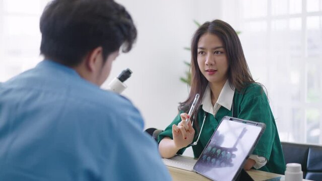 Asian doctor holding x-ray radiography on tablet to patient reviewing brain X-ray.