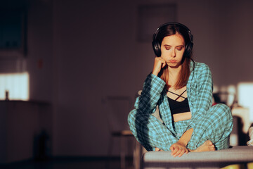 Fototapeta na wymiar Bored Woman Wearing Headphones and Pajamas at Home. Unhappy disappointed girl having negative feelings listening to music 