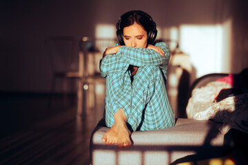 Bored Woman Wearing Headphones and Pajamas at Home. Unhappy disappointed girl having negative...