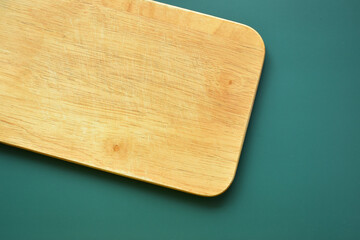 brown wooden cutting board on green background, equipment for cooking in the kitchen