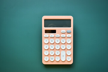 modern peach colour pastel calculator and white button on green background, business and finance...