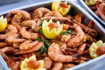 A tray of shrimp served at a buffet with lemon garnish.