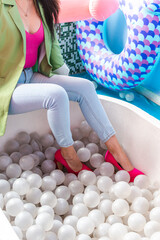 woman wearing pink slippers sitting on the edge of plastic ball pool