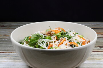 Traditional spicy rice noodle salad mixed with fresh herbal vegetable, chilly and crab stick serving in the bowl. Famous appetizer menu dressing with pickled fish sauce in Asia restaurant.
