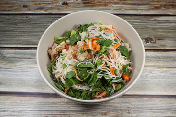 Traditional spicy rice noodle salad mixed with fresh herbal vegetable, chilly and crab stick serving in the bowl. Famous appetizer menu dressing with pickled fish sauce in Asia restaurant.