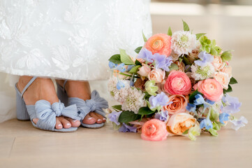 close up of bride's feet in soft blue shoes next to her colorful wedding bouquet filled with spring pastel flowers - Powered by Adobe