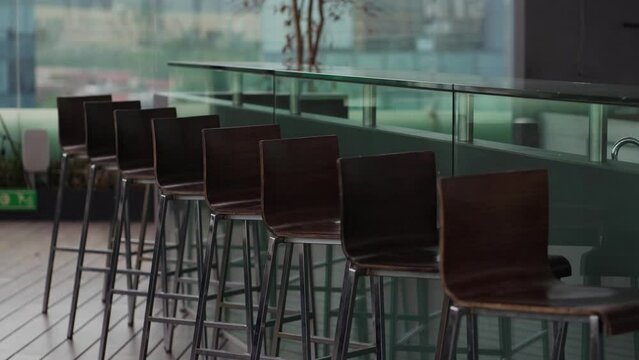 Bar stools beautifully arranged in front off glass-top bar, medium shot. Pan sideways