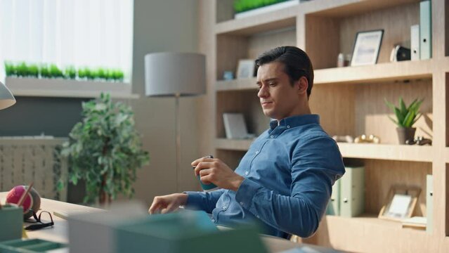 Relaxed startuper drinking coffee working office closeup. Man staring computer