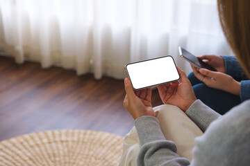 Mockup image of a couple woman holding and using a white mobile phone with blank desktop screen...