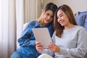 Portrait image of a young couple women holding and using digital tablet together