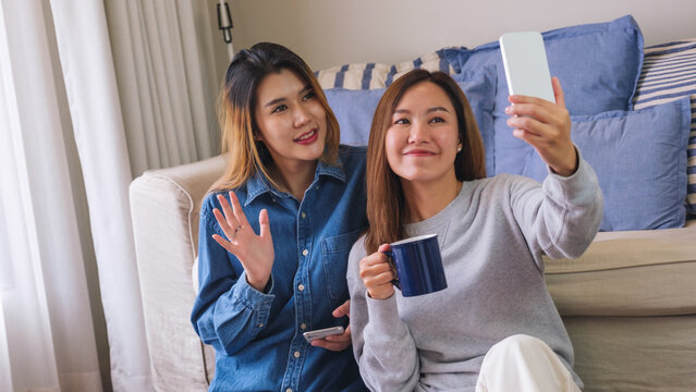 Portrait image of a young couple women using mobile phone to take a selfie together