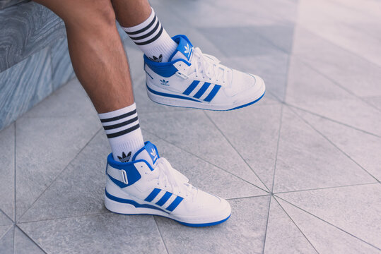 Adidas Forum Mid white and blue sneakers on man's feet in the street, a closeup on May 20, 2023 in Bangkok, Thailand.