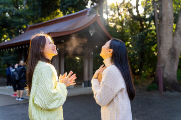 Asian woman friends travel and praying at traditional Meiji Jingu Shrine in Tokyo city, Japan....
