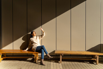 Obraz premium Happy Asian woman sitting on outdoor bench during shopping at Tokyo city, Japan. Attractive girl enjoy and fun urban outdoor lifestyle travel city street in autumn holiday vacation.
