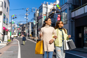 Happy Asian woman friends walking and shopping together at Shibuya district, Tokyo, Japan in...