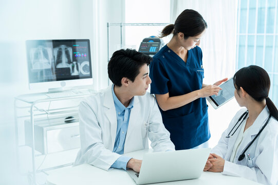 Doctors having a meeting while looking at electronic tablets and materials