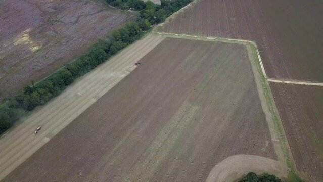 Wide Aerial Footage of Tractor Working in Dusty Field on Farm