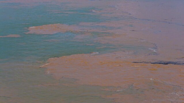Muddy water washing into clean bule aqua river Mekong at the start of south east Asia monsoon season.