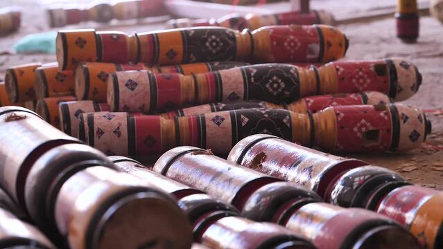 Piles Of Wooden Colourful Charpai Traditional Leg Posts Resting On Workshop Floor. Low Angle