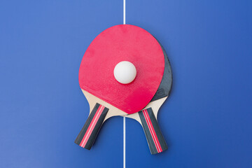 Two table tennis or ping pong rackets and balls on a blue table