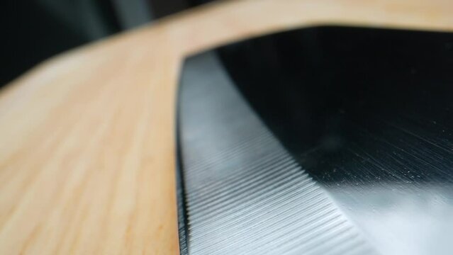 Mesmerizing macro footage capturing the intricate patterns of a Damascus steel kitchen knife resting gracefully on a polished wooden cutting board.
