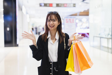 Happy smile woman wear black suit cheerful holding shopping bag colorful in supermarket. Female relaxation at shopping mall in holiday.