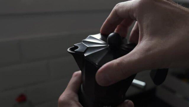 hand screw on italian moka pot, in kitchen to prepare coffee

