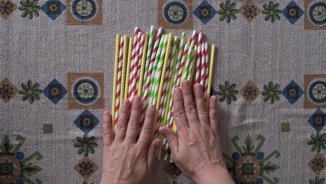 woman's hands placing colored biodegradable disposable paper straws on the table
