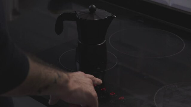 putting coffee pot on the electric stove and starting the electric stove by pressing the touch screen
