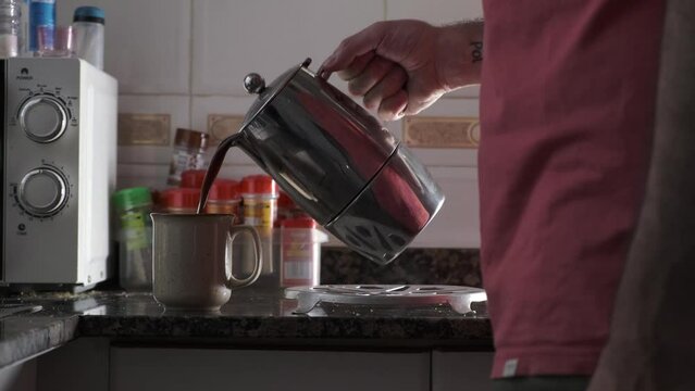 hand pouring coffee in cup in the kitchen. hand holding cup of freshly brewed coffee

, 