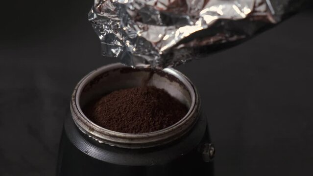 pour ground coffee into Italian moka pot, close-up
