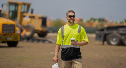 Fototapeta premium contractor man at construction site. contractor check building during break. male contractor at working location. worker at coffee break. contractor in hard hat and safety vests in building site