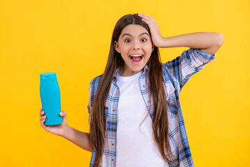 surprised teen girl holding beauty cosmetics. Teen girl use beauty cosmetics for hair. teen girl with high-quality shampoo beauty cosmetics isolated on yellow. teen girl and beauty product cosmetics