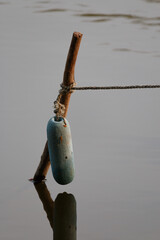 old fishing float and rope on a pole in water