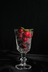 ripe red berries in a glass with a sparkling drink with bubbles and green mint leaves. summer drinks. non-alcoholic cocktail