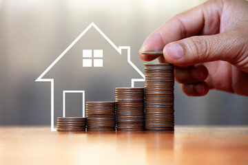 Real estate market growth and home investment concept Human hands are stacking coins and a model house with increasing piles of coins. Property Tax and Inflation Insurance for Personal Finances