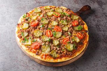 Tasty Pizza is topped with a creamy burger sauce, ground beef, cheese and pickles closeup on the wooden board on the table. Horizontal