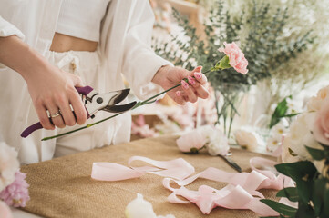 florist iscutting a branch with a pruner  in a flower shop. Floral design studio, making decorations and arrangements. Flower delivery, order creation. Small business. No face closeup