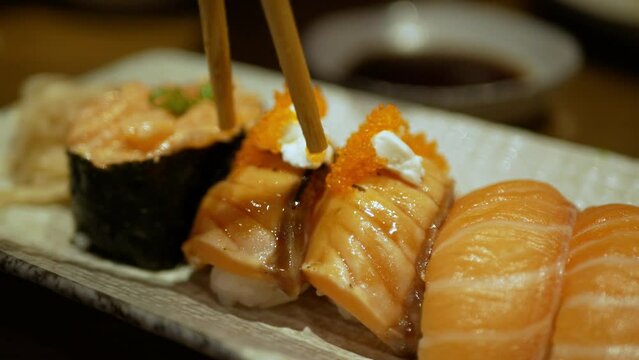 view to a plate of shushi while using chopstick to grab tuna shushi to eat in japanese restaurant
