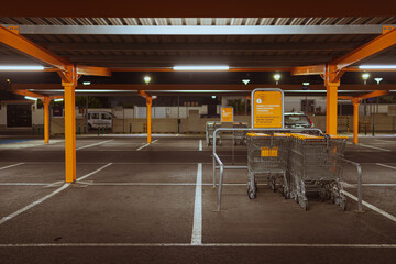 Many rows of orange trolleys outside the store with a close-up of the parking lot, there is a place for an inscription