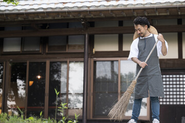 古民家や古い家の庭を掃除して手入れする男性