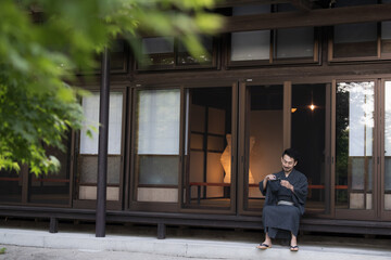 Fototapeta na wymiar 日本の田舎や旅館に旅行にきて縁側でお酒を飲む浴衣の日本人男性　広角