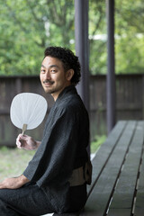 Japanese man in yukata relaxing on the porch with an uchiwa fan. Let's go to Japan for images of...
