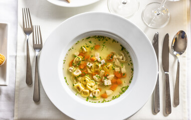 Top view of a chicken soup with tortelini served on a fancy table