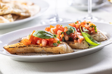 Detail of bruschetta on sourdough bread with chopped tomatoes and fresh basil leaves
